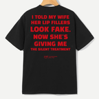 A black short-sleeve t-shirt hanging on a wooden hanger against a light gray background, featuring a humorous red text graphic on the back.