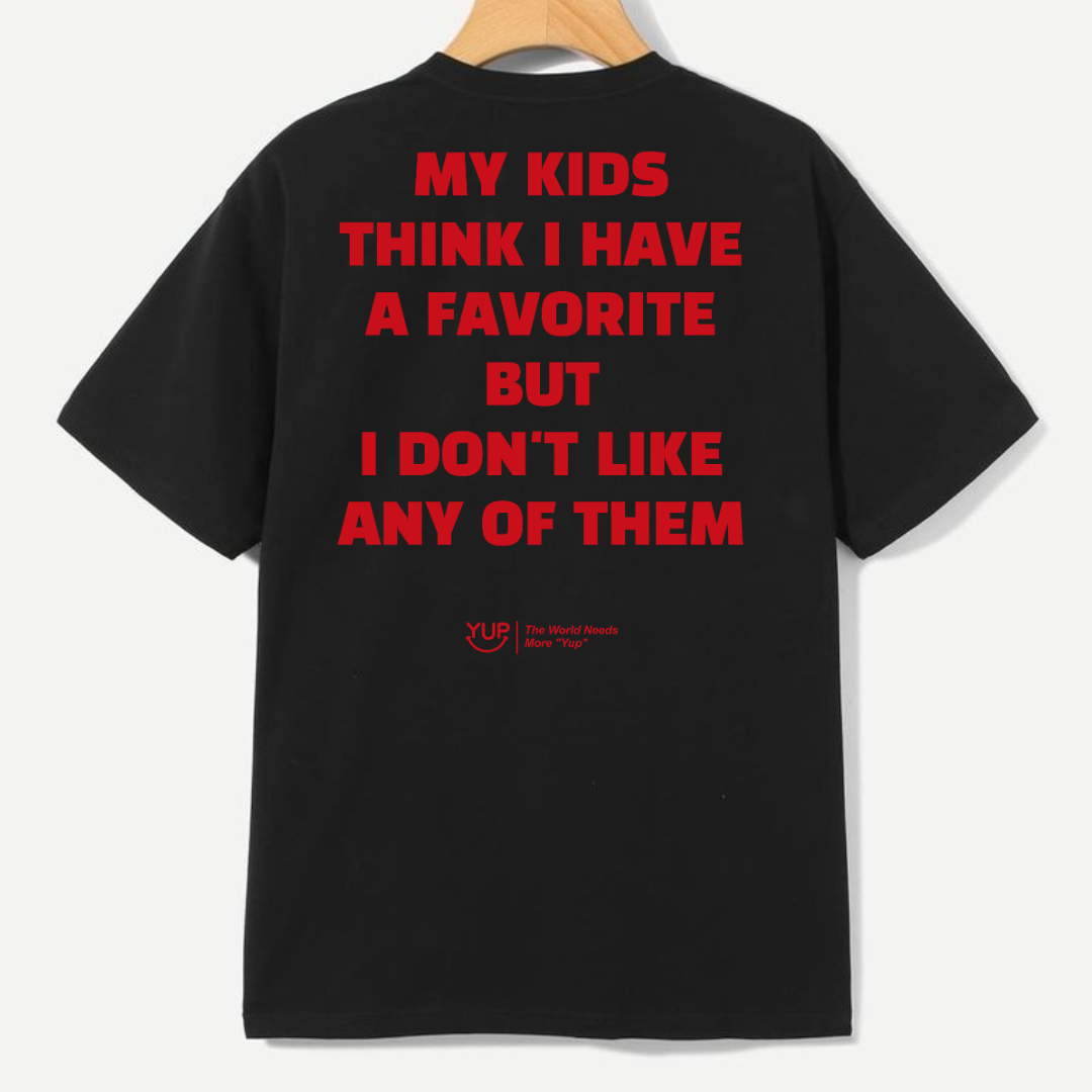 A black short-sleeve t-shirt hanging on a wooden hanger against a light gray background, showing the back with bold red text that reads 'MY KIDS THINK I HAVE A FAVORITE BUT I DON'T LIKE ANY OF THEM'.