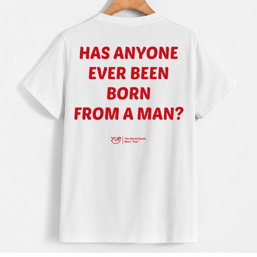 White short-sleeve T-shirt hanging on a wooden hanger against a light gray background, showing the back with large red text reading 'HAS ANYONE EVER BEEN BORN FROM A MAN?' and a small red YLD logo below.