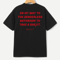A black short-sleeve t-shirt hanging on a wooden hanger, showing the back with bold red text that reads 'ON MY WAY TO THE GENDERLESS BATHROOM TO TAKE A SHE/IT.' and a small red YUP logo underneath.