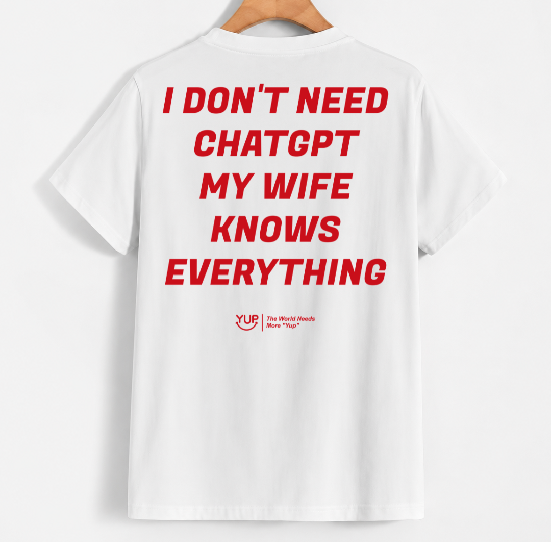 White short-sleeve t-shirt hanging on a wooden hanger, featuring bold red text on the back that reads 'I DON'T NEED CHATGPT MY WIFE KNOWS EVERYTHING' with a small red 'YUB' logo underneath.