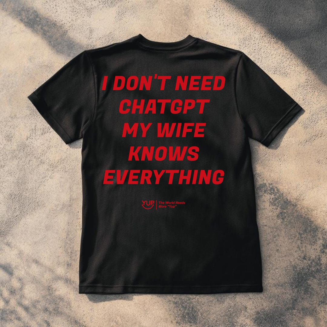 A black short-sleeve t-shirt laid flat on a textured concrete surface with dappled shadows. The back of the shirt features the phrase 'When you Excel They will spreadsheet about you' printed in a bold red font.