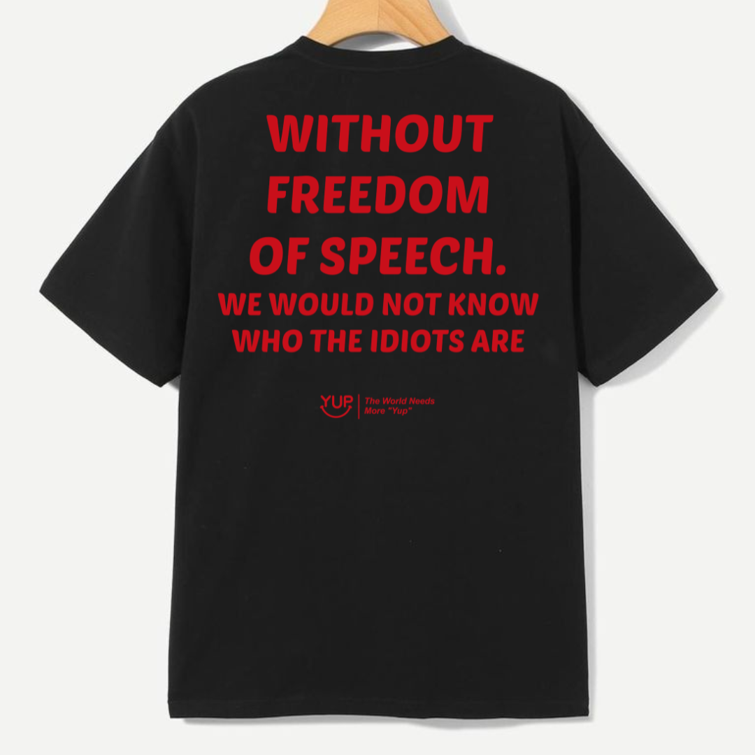 Black short-sleeve T-shirt hanging on a wooden hanger, showing the back with large red text that reads 'WITHOUT FREEDOM OF SPEECH. WE WOULD NOT KNOW WHO THE IDIOTS ARE' and a small red YUP logo near the lower back.