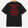 A black short-sleeve t-shirt hanging on a wooden hanger, showing the back with bold red text that reads 'When you Excel They will spreadsheet about you'.