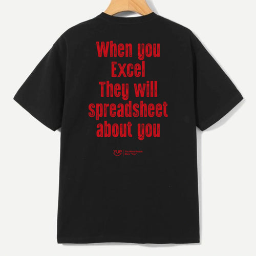 A black short-sleeve t-shirt hanging on a wooden hanger, showing the back with bold red text that reads 'When you Excel They will spreadsheet about you'.